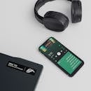 A flat lay of a smartphone, laptop, and headphones showcasing a sleek tech setup.